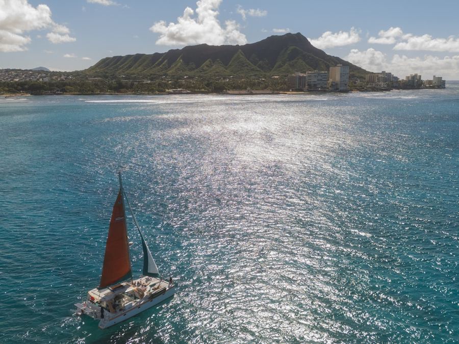 A catamaran cutting across brilliant blue water off Oahu